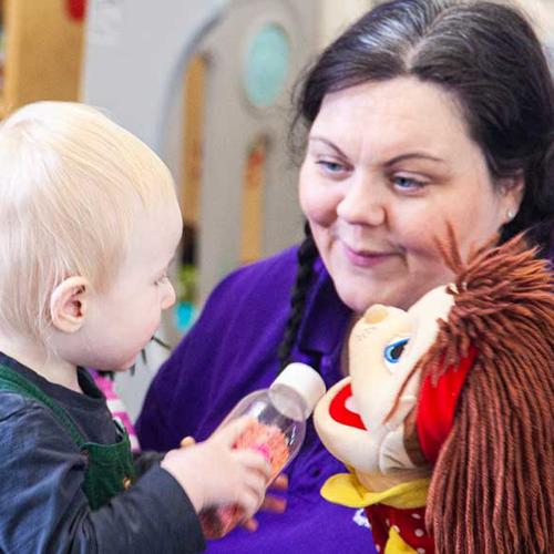 33 Young boy and staff member playing with a soft doll